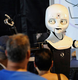 A robot points into the distance as people look on in the foreground. A robot points into the distance as people look on in the foreground.